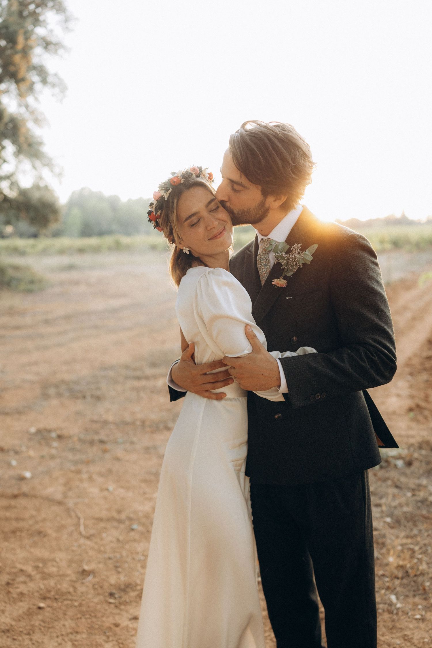 Romantic golden hour wedding portraits show couple embracing in a rustic outdoor setting.