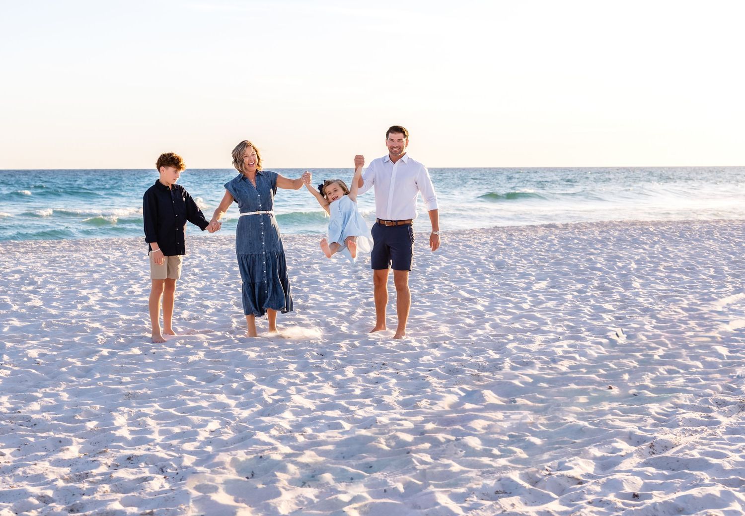 People walking together on pristine white sand beach during sunset along the ocean shore.