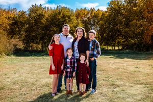 A group poses together outdoors in coordinated red and blue outfits during a fall photo session in a grassy field.