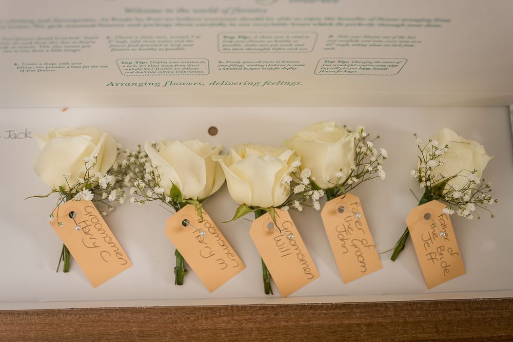 Delicate white roses with name tags arranged in a row against a light background.