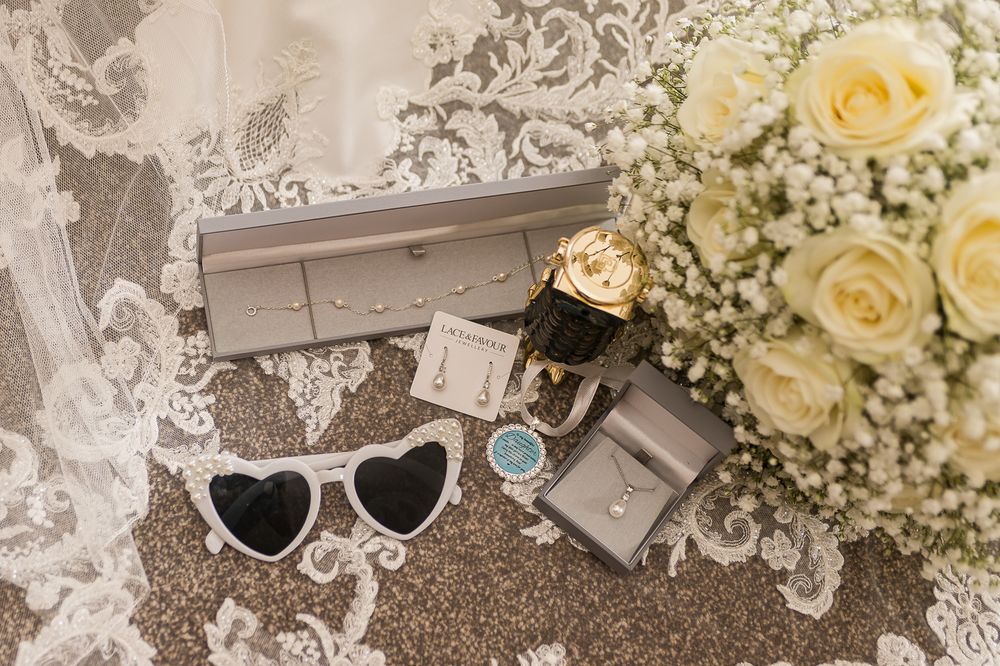 White roses and baby's breath bouquet arrangements with name cards on lace tablecloth.