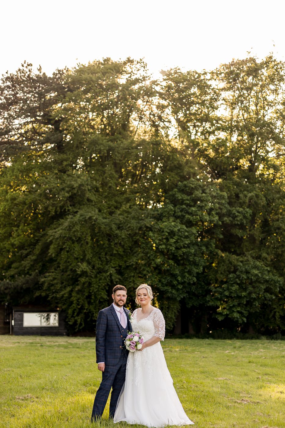 Newlyweds pose for portraits in a scenic garden setting at sunset.