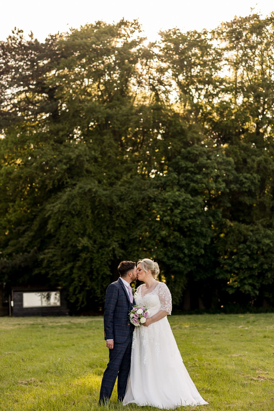 Romantic wedding portrait of couple in formal attire against natural garden backdrop.