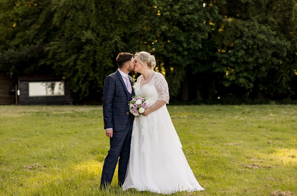 Elegant wedding couple poses in outdoor garden setting during golden hour.