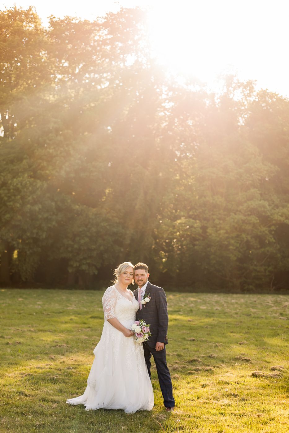 Wedding portraits captured in golden sunlight on a serene grassy field.