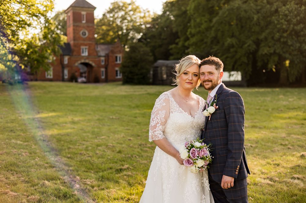 Wedding couple poses in front of a historic brick building during golden hour.