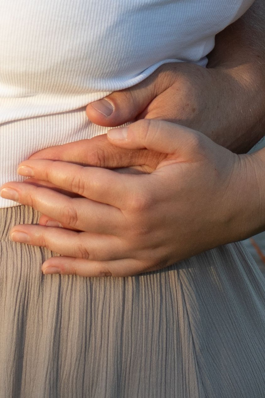 Two hands rest gently on a white pleated fabric surface in soft natural lighting.
