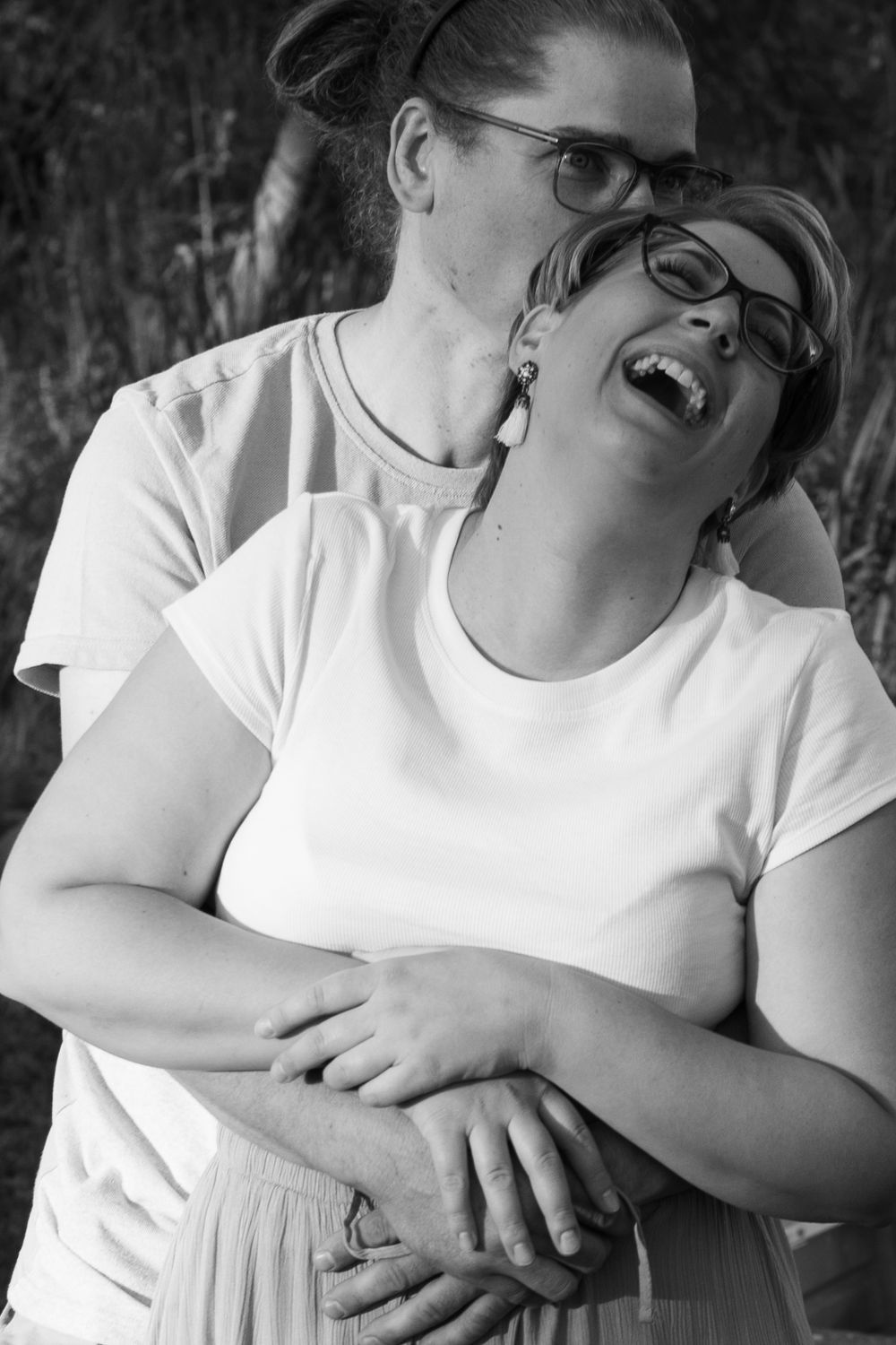 A joyful candid series of black and white photos showing two people laughing together while wearing white shirts.