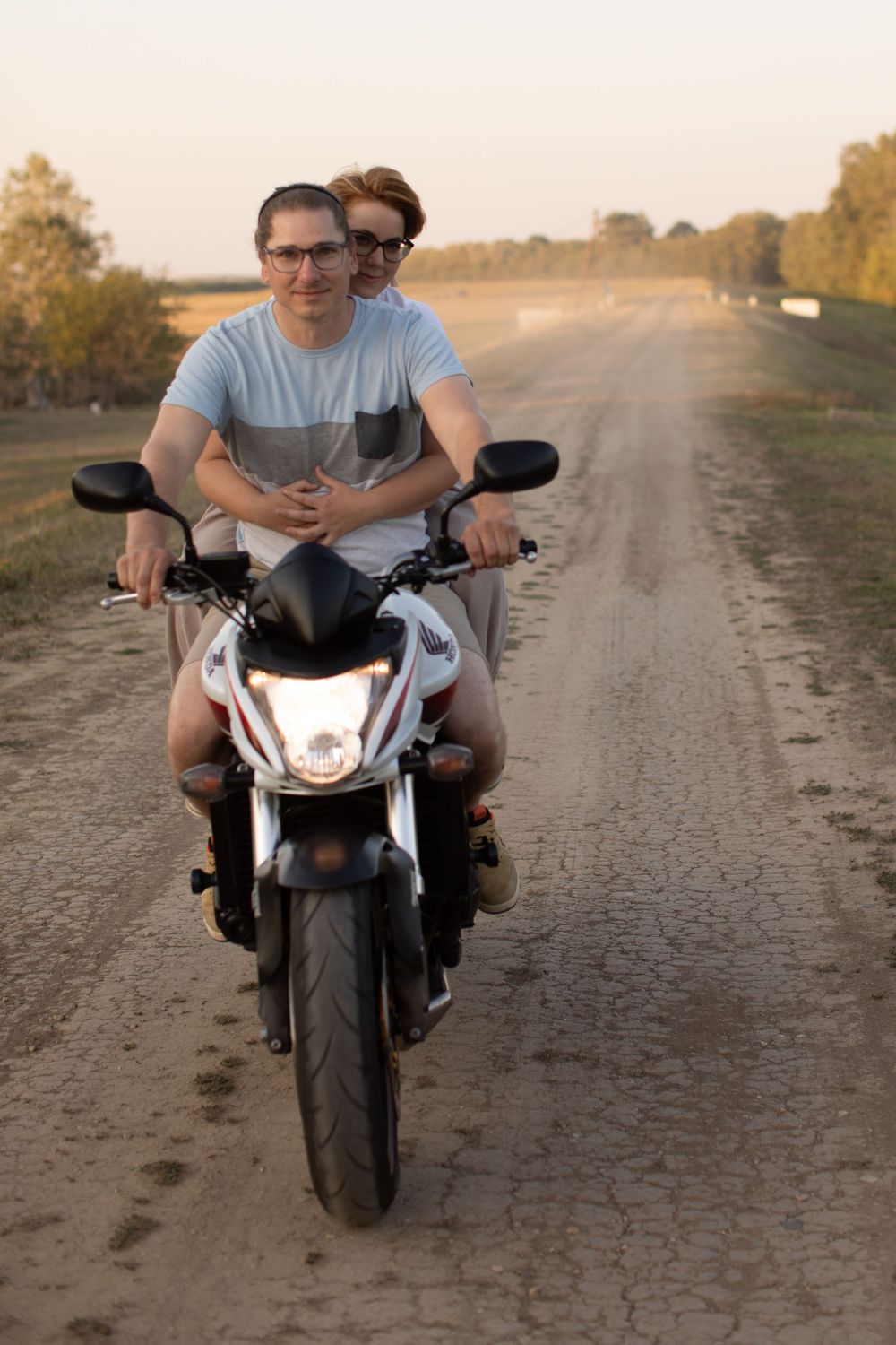 White motorcycle parked on a dirt road during golden hour sunset.