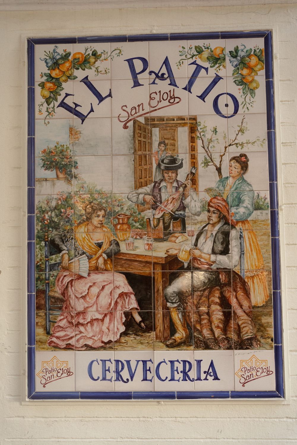 Vintage Spanish ceramic tile murals depicting traditional tavern scenes with people drinking and socializing in a cerveceria.