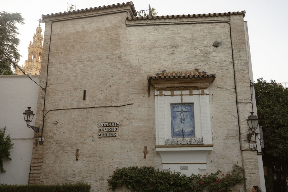 A series of white Mediterranean-style buildings with terracotta roofs and rustic architectural details line a street.