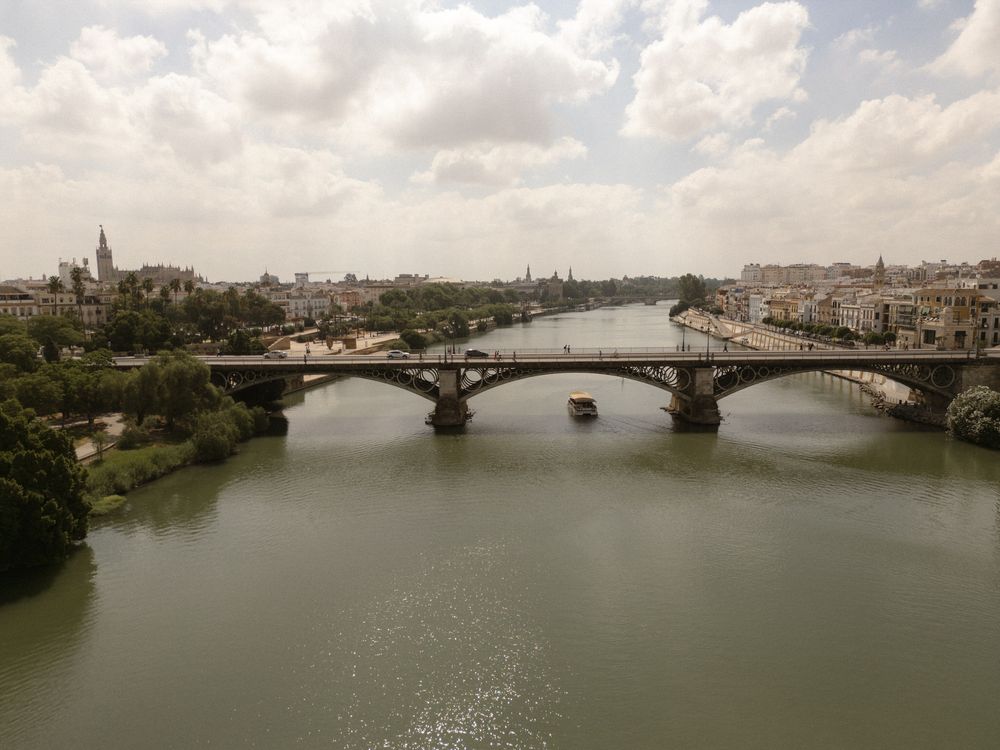 A panoramic view of a city skyline with bridges spanning across a wide river on a cloudy day.