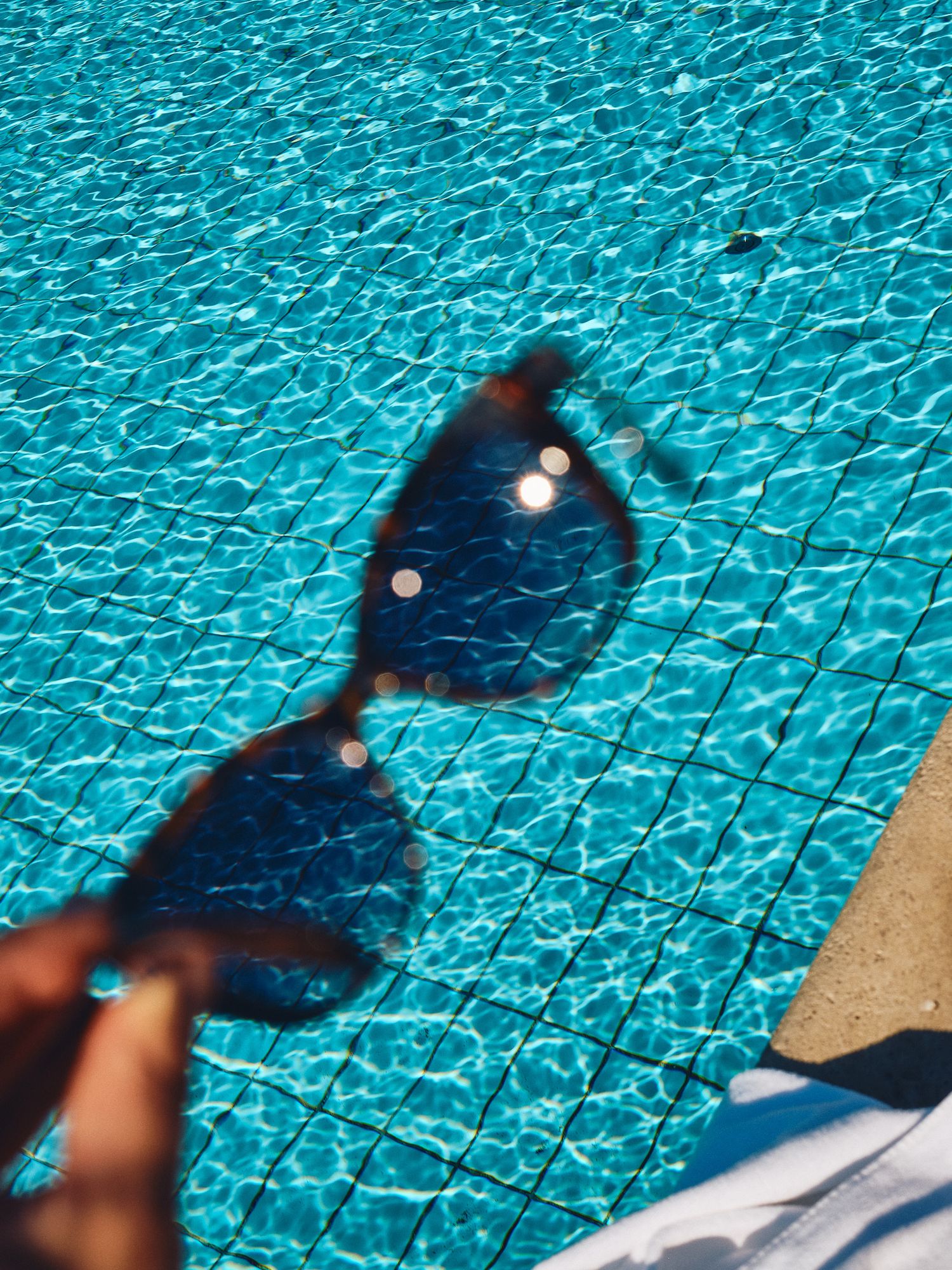 A serene swimming pool with thatched umbrellas and wooden deck chairs overlooking scenic countryside views.