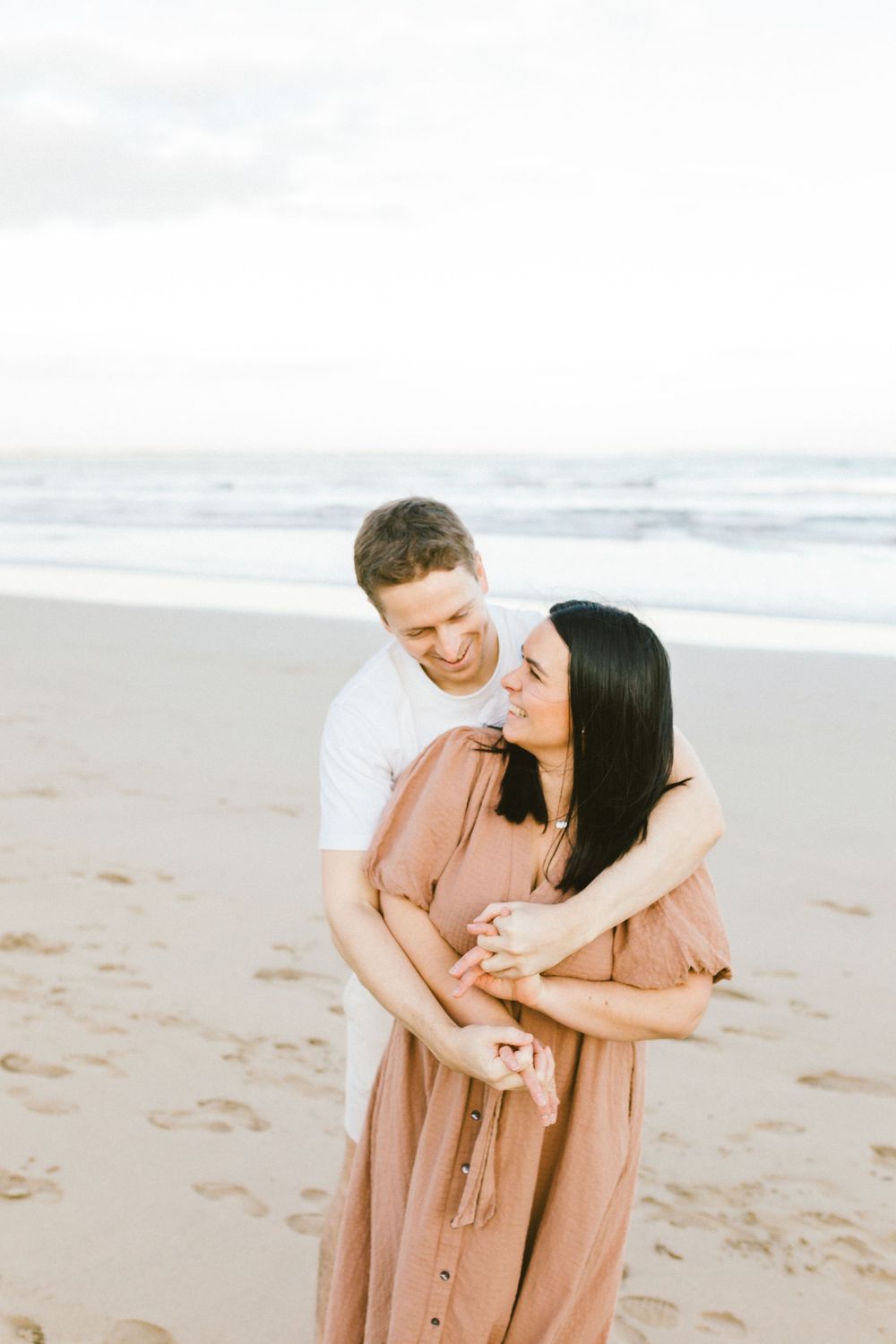 Romantic couple sharing tender moments together while walking along a sandy beach at sunset.