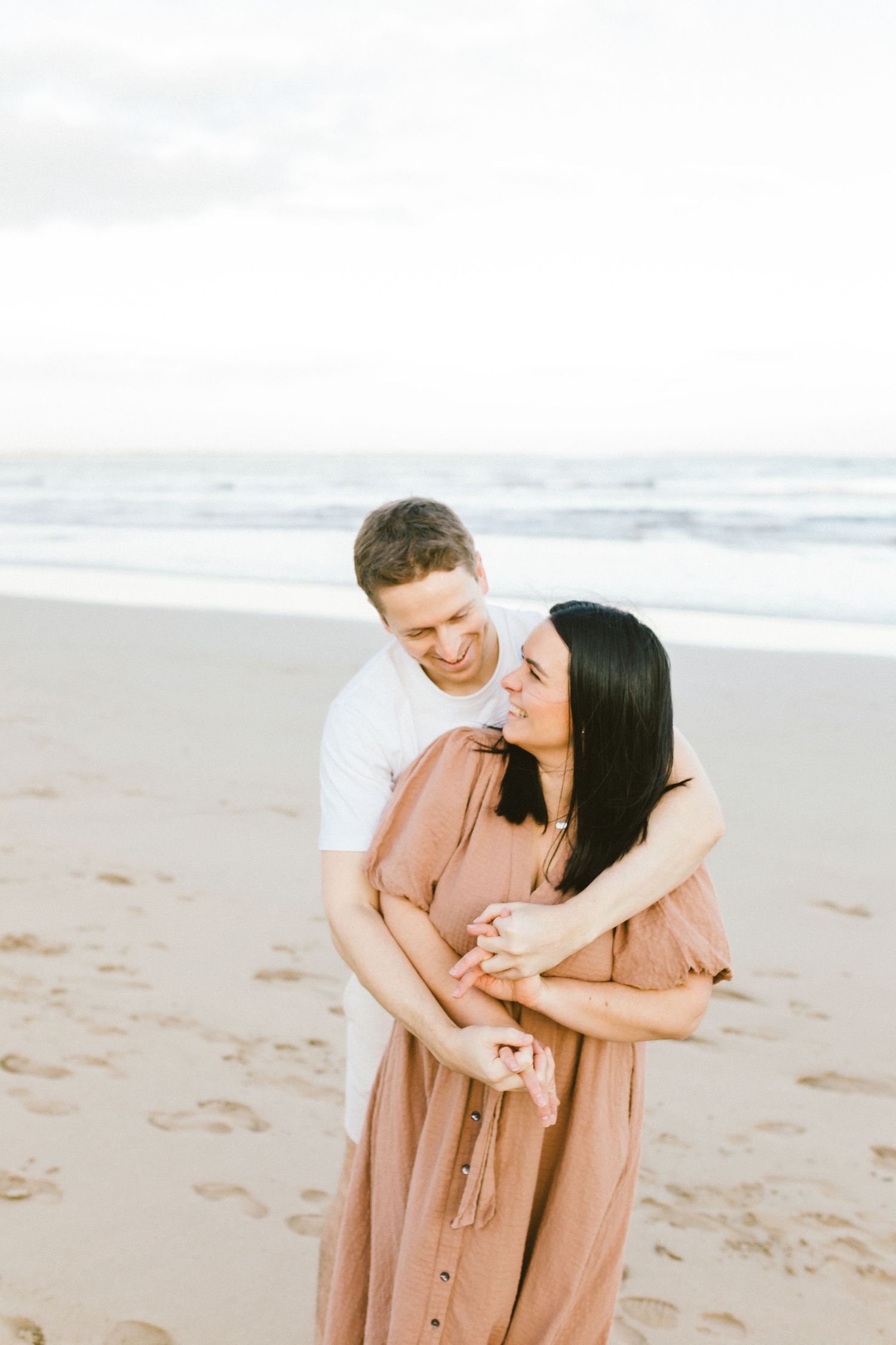Romantic couple sharing tender moments together while walking along a sandy beach at sunset.