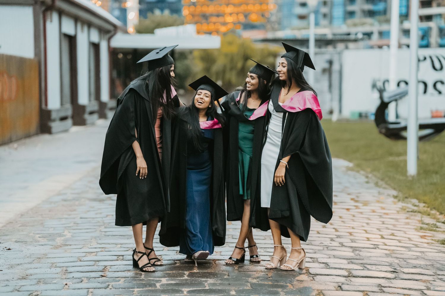 A group in graduation caps and gowns walks together on a stone path during an outdoor ceremony.