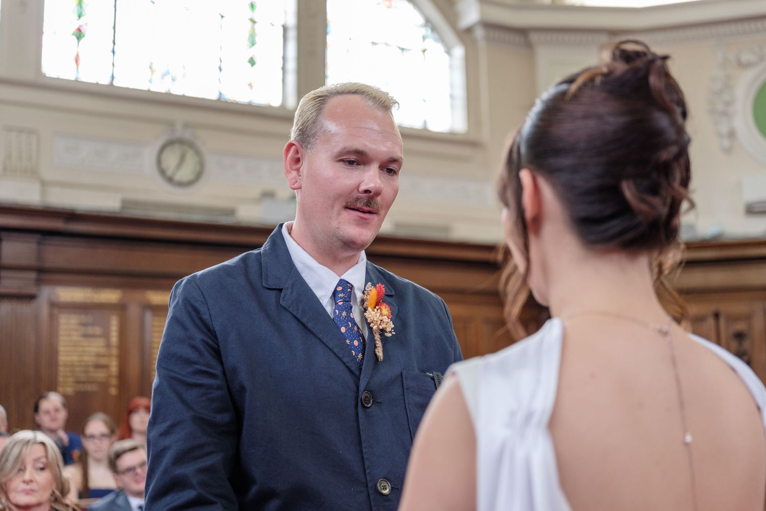 A wedding ceremony taking place in an elegant courthouse with the couple exchanging vows in front of guests.