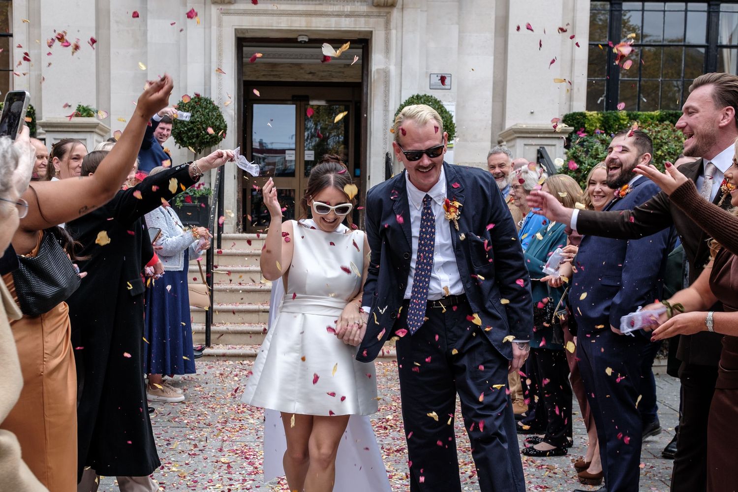 Wedding guests shower a couple with confetti as they exit the courthouse building in celebratory moment.