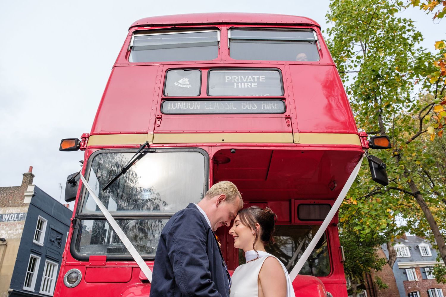 A red double decker bus being converted into a mobile bar with a wooden interior and outdoor seating area.
