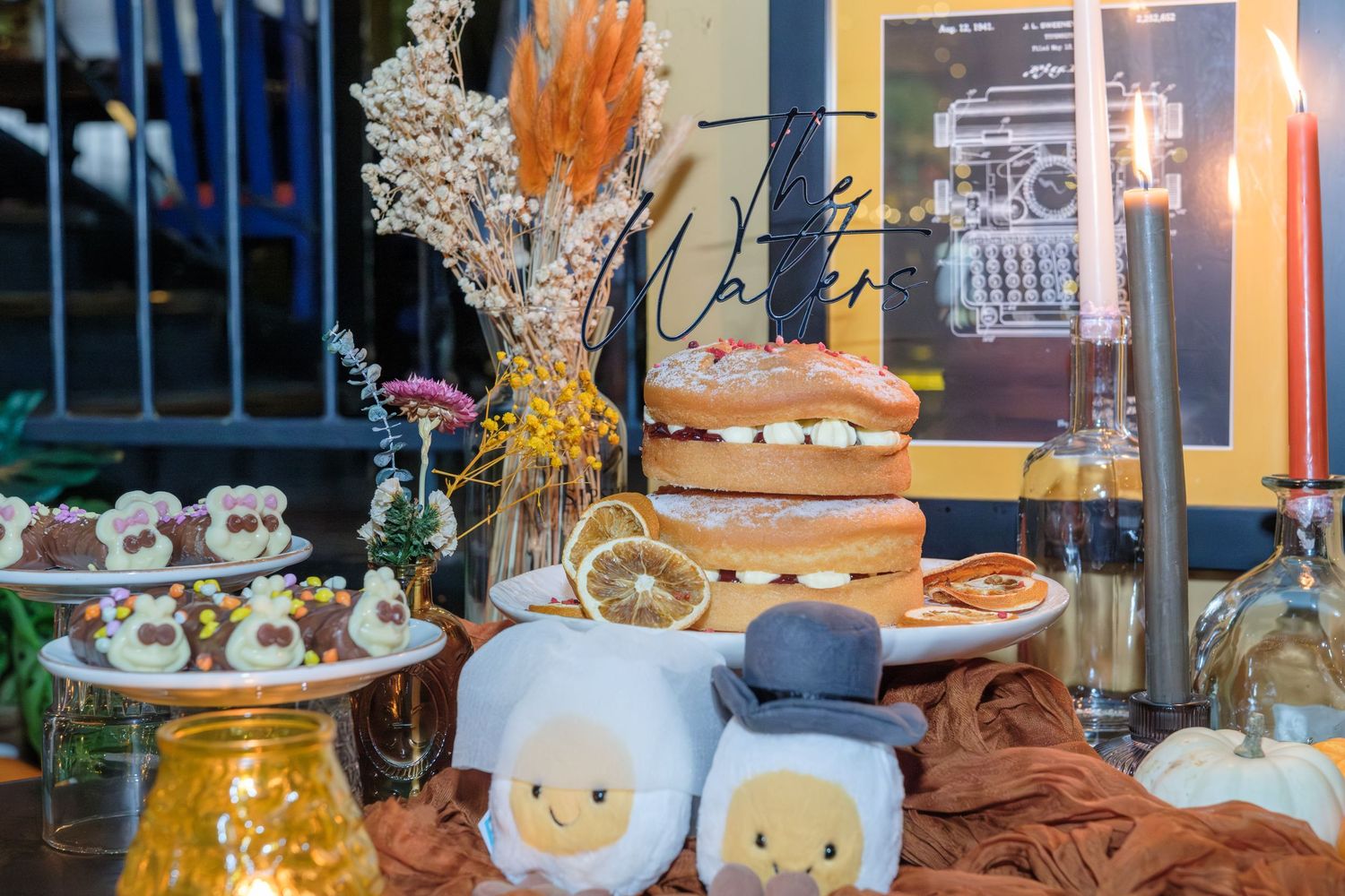 A colorful display of desserts and pastries arranged on tiered stands with decorative elements at a cafe or bakery.