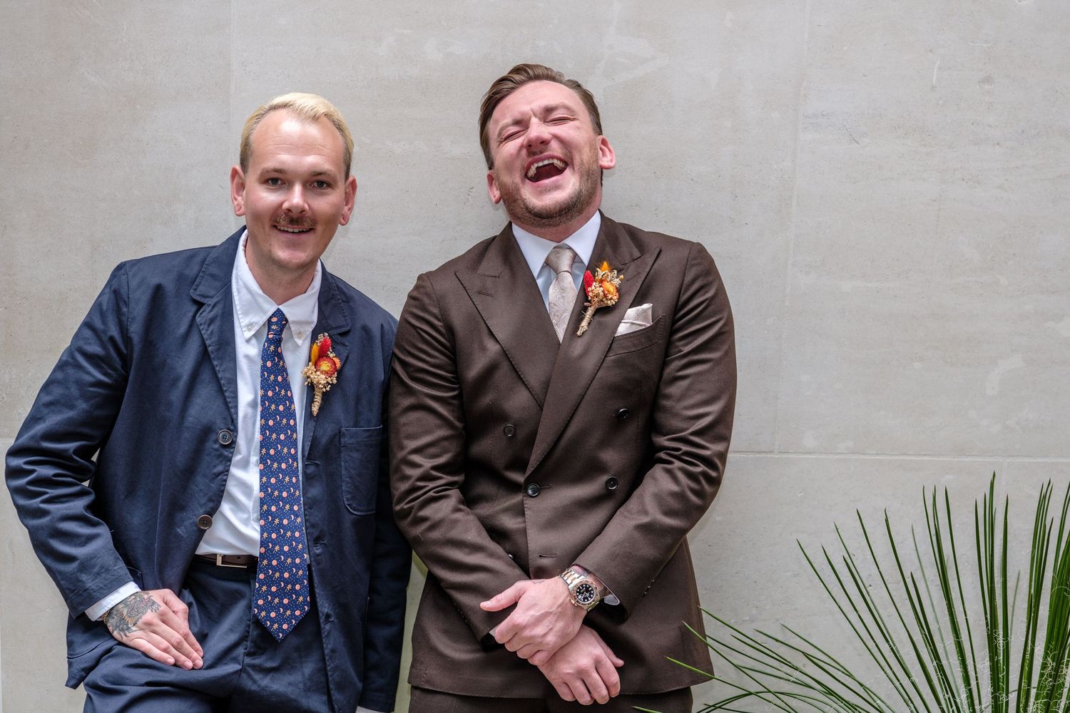 Two people in business attire share a laugh while sitting together at a professional event.