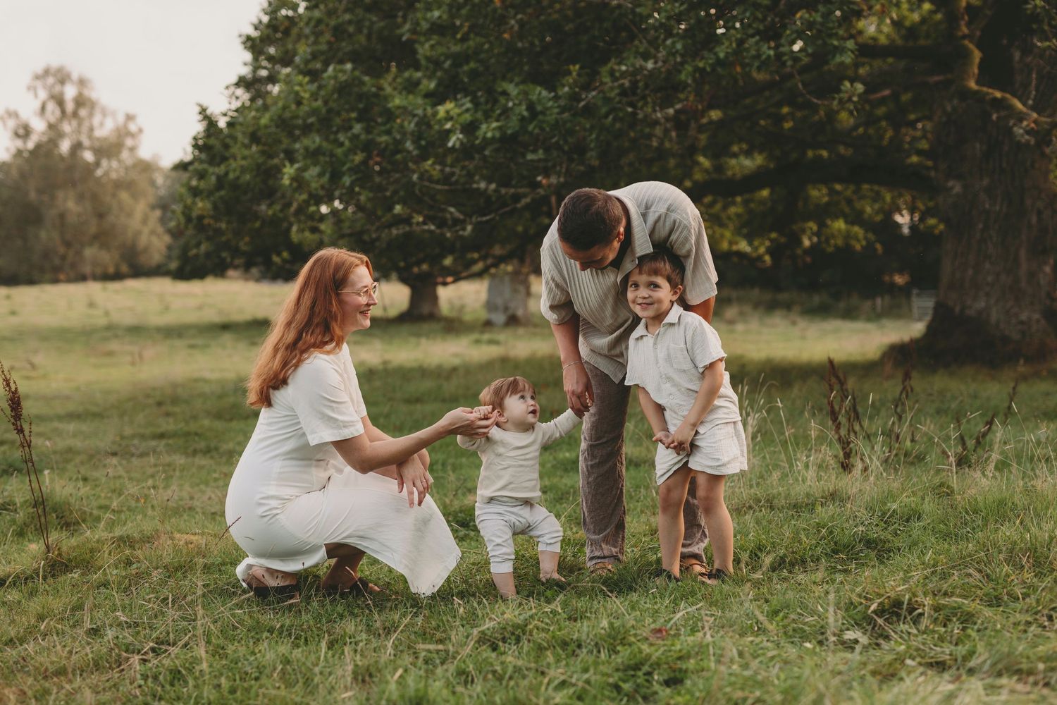 A family shares a tender moment together in a sunlit meadow during golden hour.