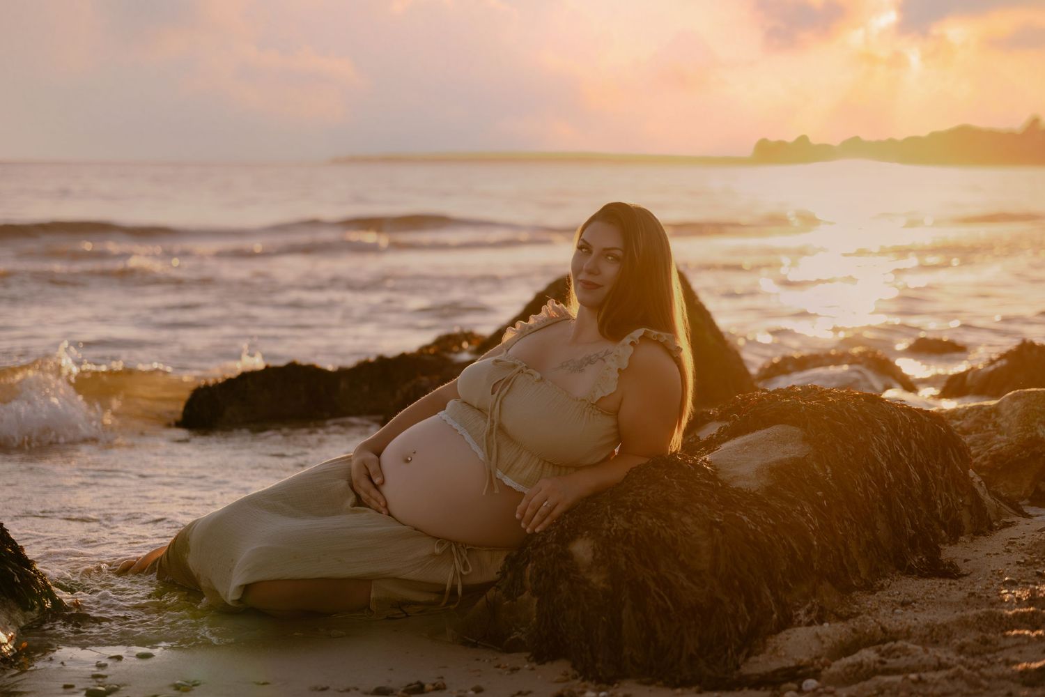 A woman's pregnant belly that is being poked by her young daugther's finger, no faces are visible.