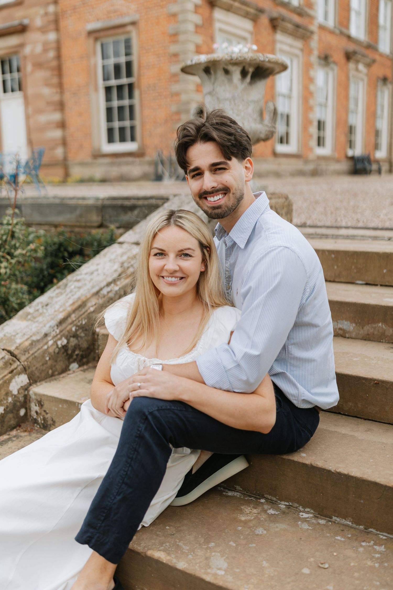 Rustic outdoor wedding scene with couple posing on fallen logs in a natural field setting.