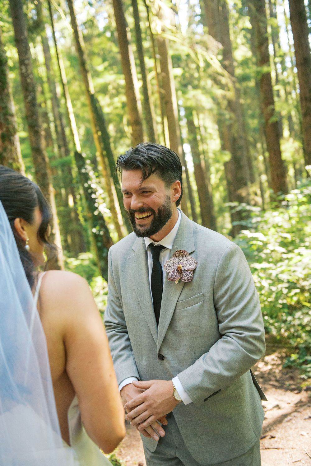 A joyful wedding moment captured in a sunlit forest setting.