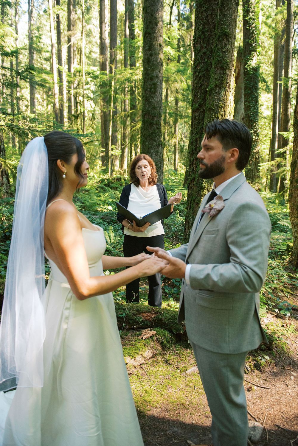 Wedding couple dances together in a lush green forest setting.