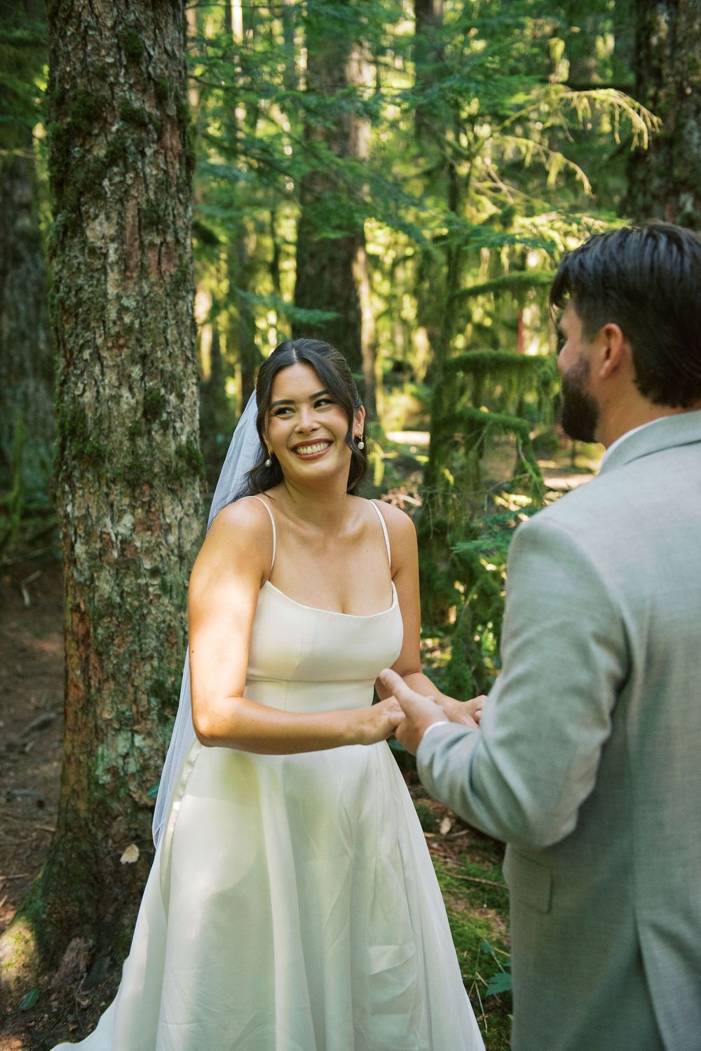 A joyful wedding ceremony moment captured between a bride and groom in a lush forest setting.