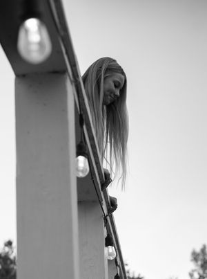 Artistic black and white composition showing someone leaning against architectural pillars.