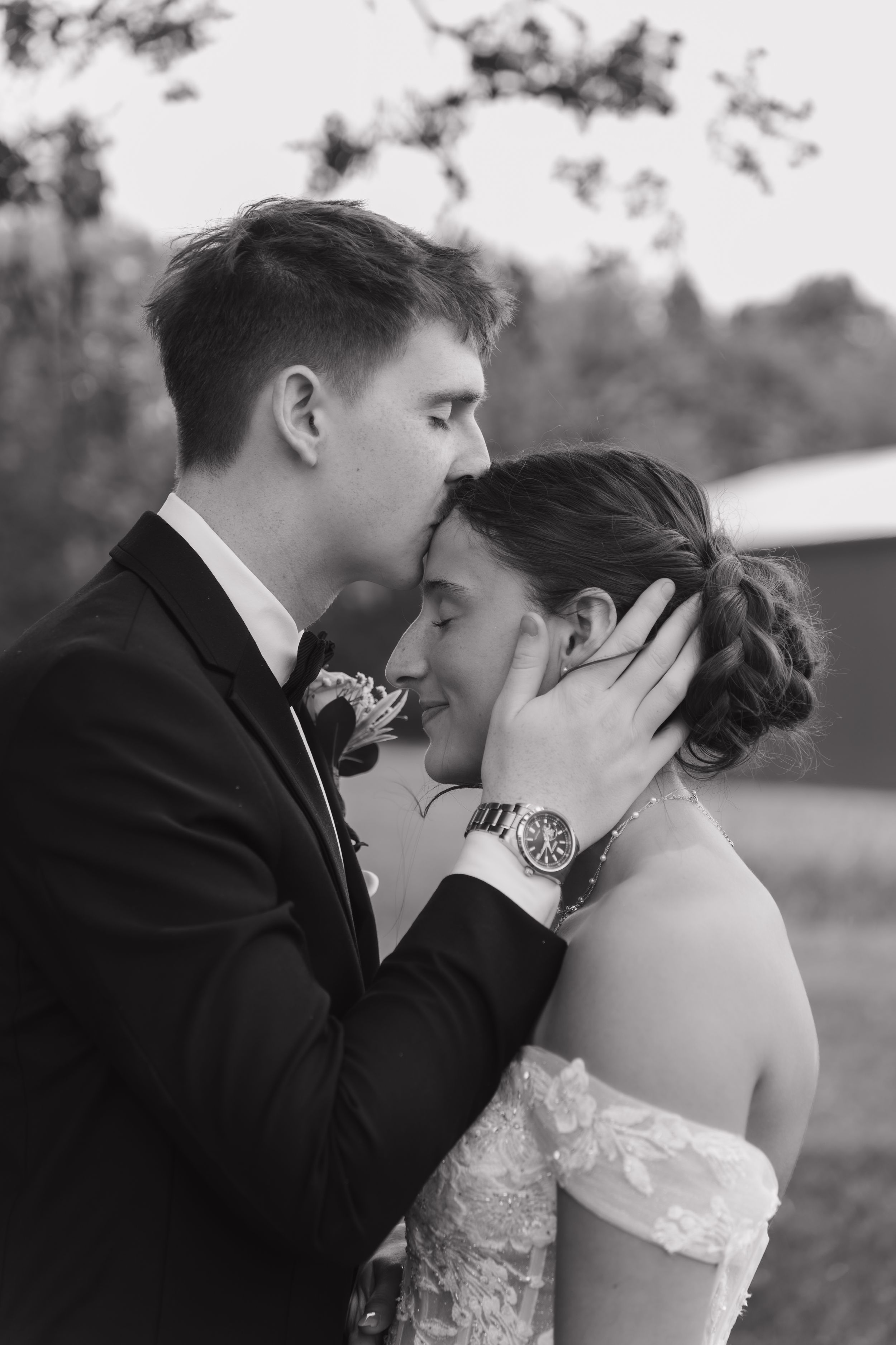 Black and white wedding portrait showing intimate moment between bride and groom in formal attire.