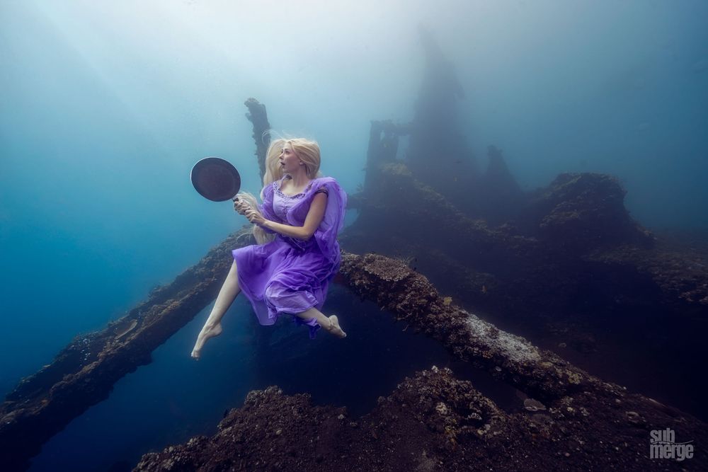 Underwater photographer captures ethereal scene of diver exploring dark ocean depths with beams of light.