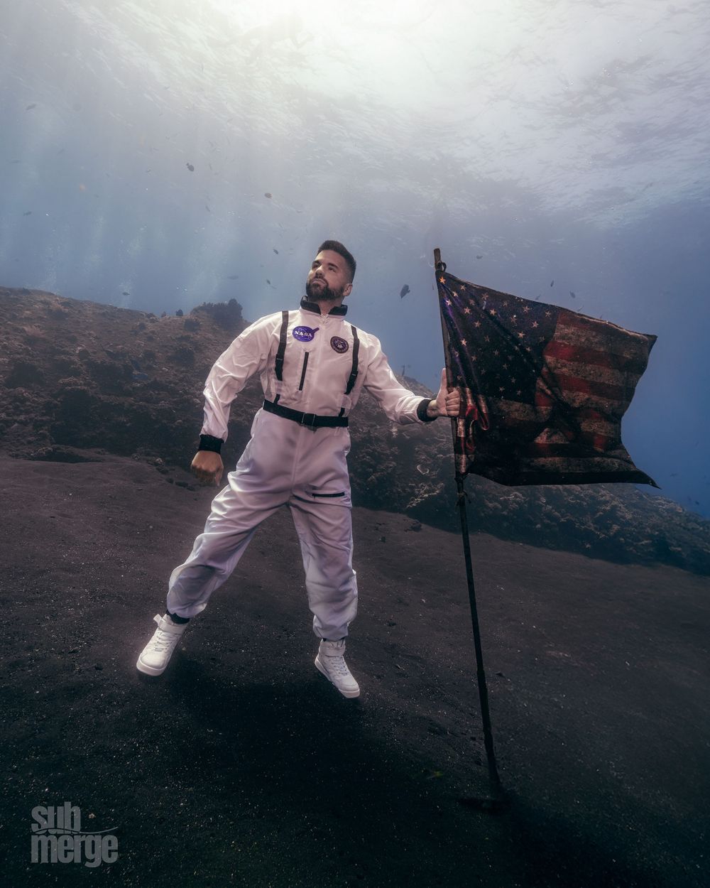 A person in a white hazmat suit performs levitating poses against a moody sky background.