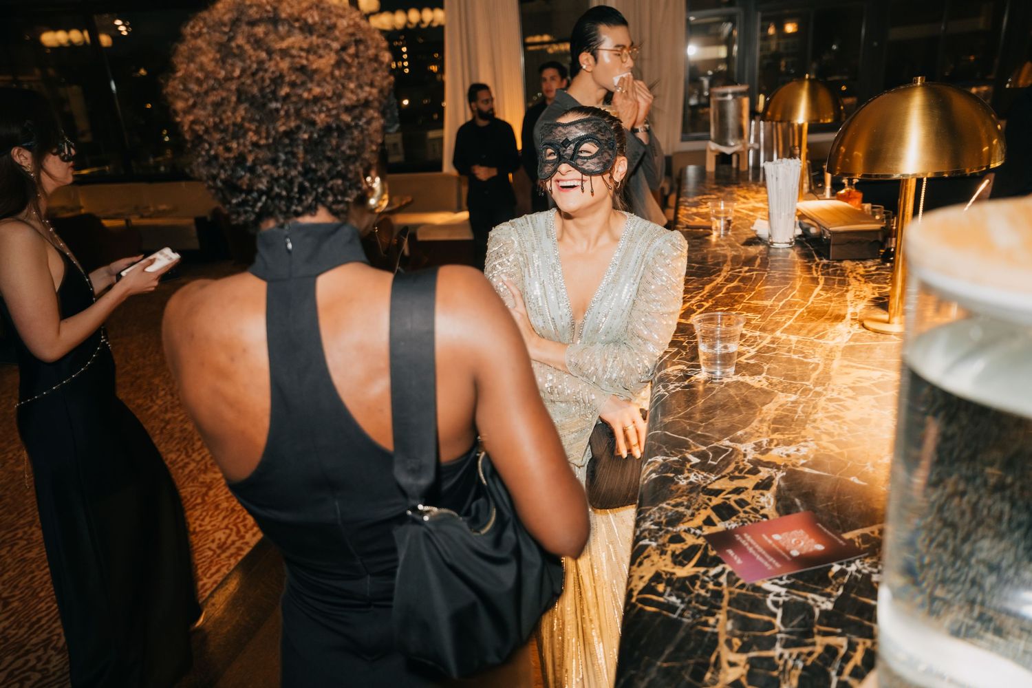 A wedding reception celebration with guests dancing and mingling under warm lighting at an indoor venue.