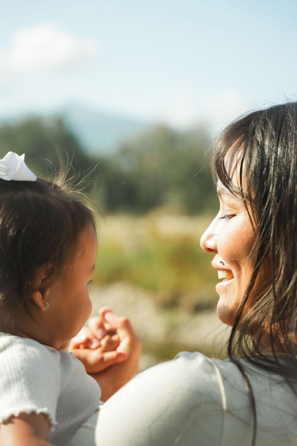 A tender moment captured in warm sunlight shows a parent and child sharing a joyful connection outdoors.