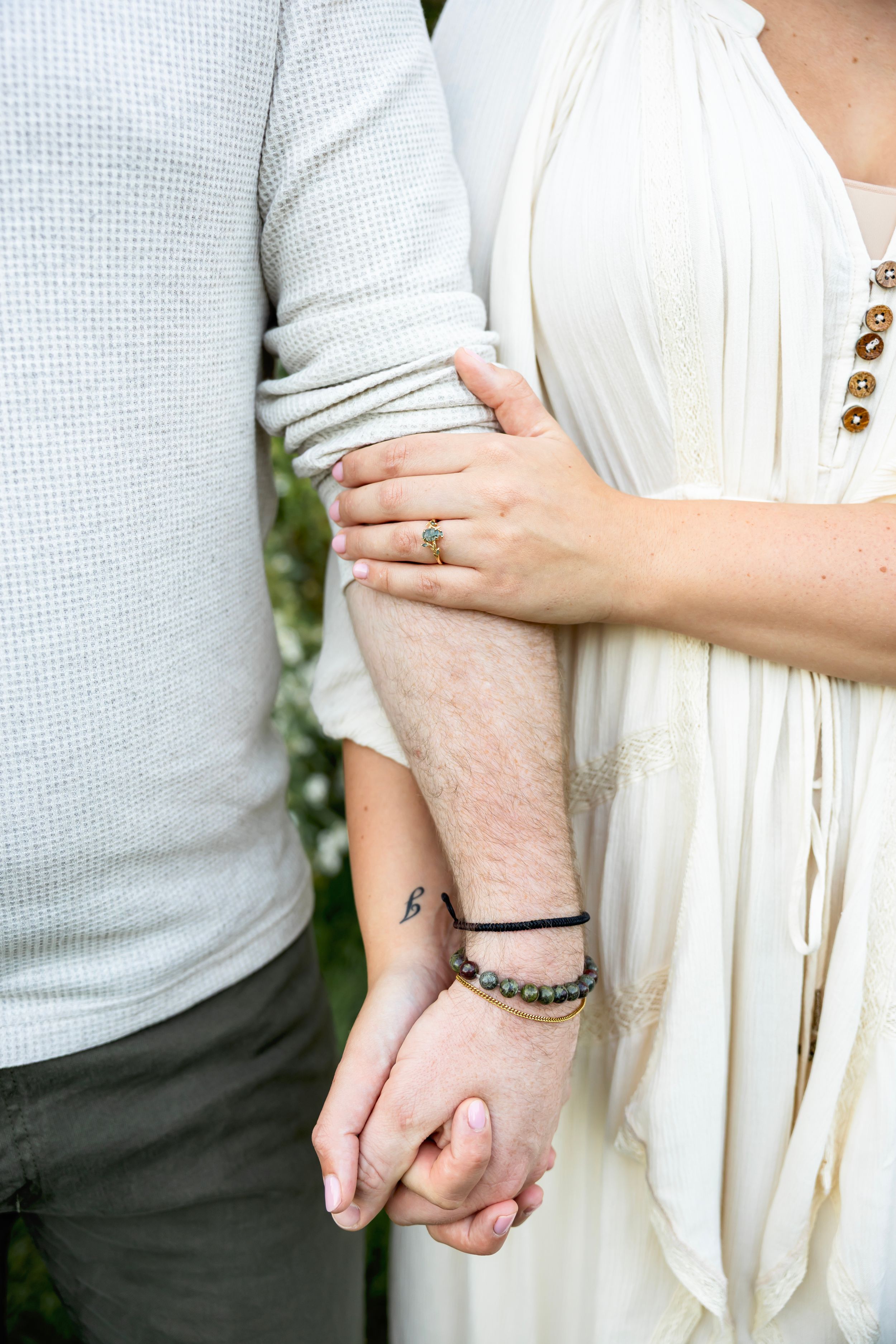 Close-up shots showing hands and arms embracing, with one person wearing a white dress and another in light gray.