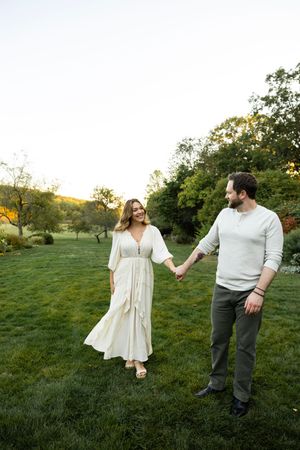 A couple enjoys a romantic sunset moment in a grassy field during their engagement photoshoot.