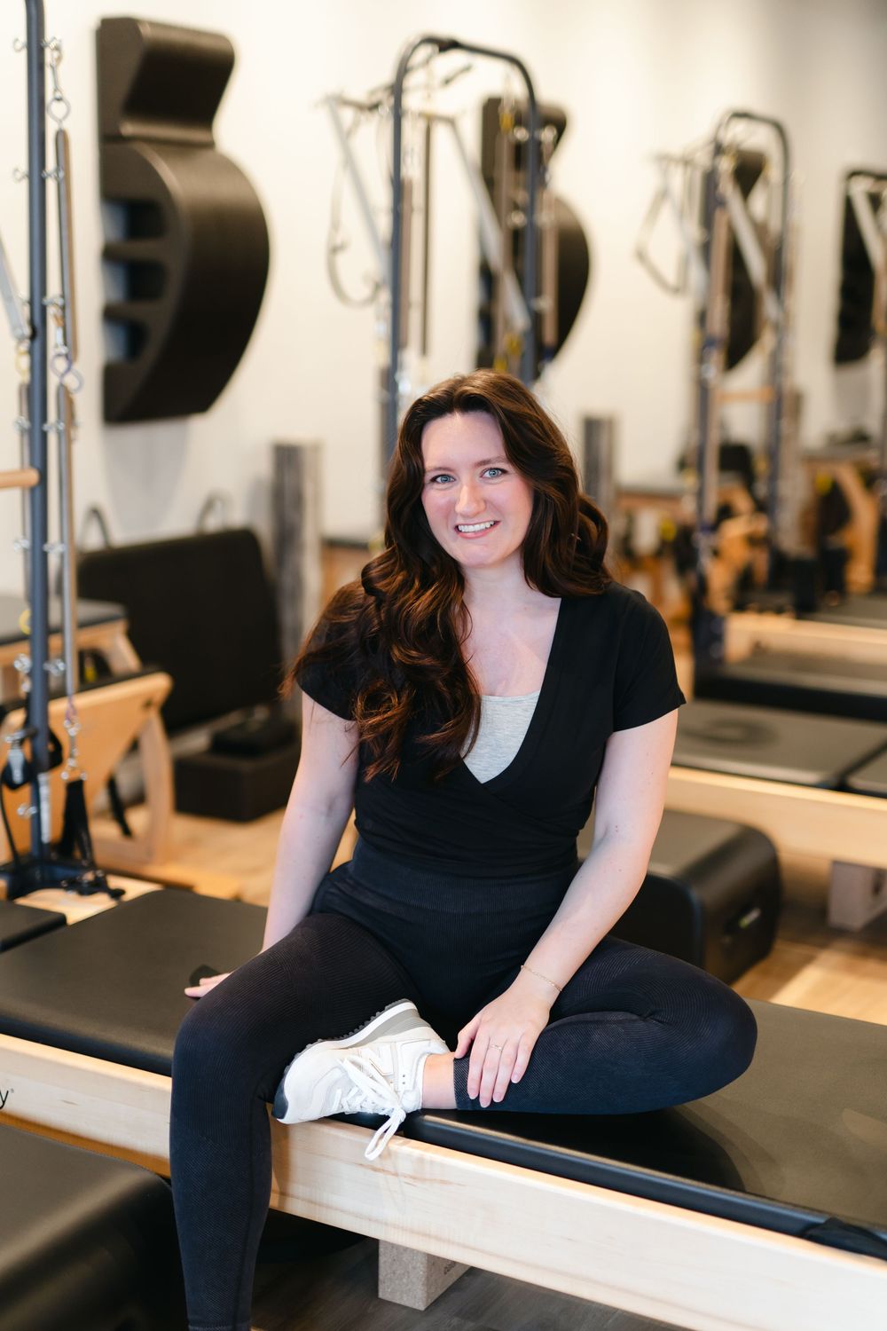 Person in black workout clothes smiling while resting on fitness equipment during a training session.