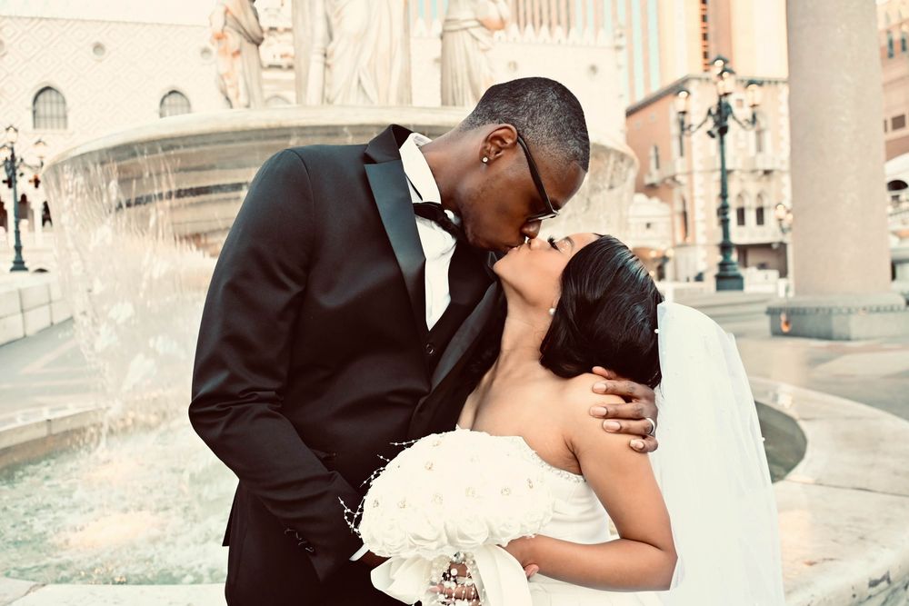 Newlyweds share a tender kiss by the fountain outside The Venetian Las Vegas hotel.