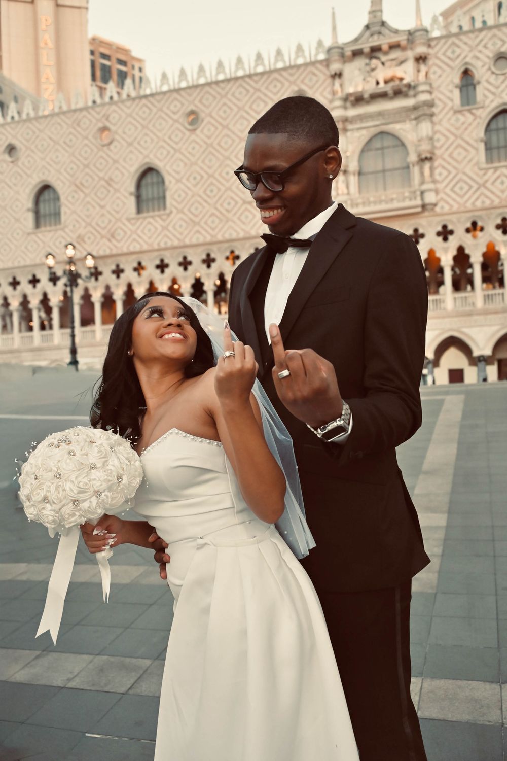 Happy couple displaying wedding rings while laughing together outside The Venetian Las Vegas.