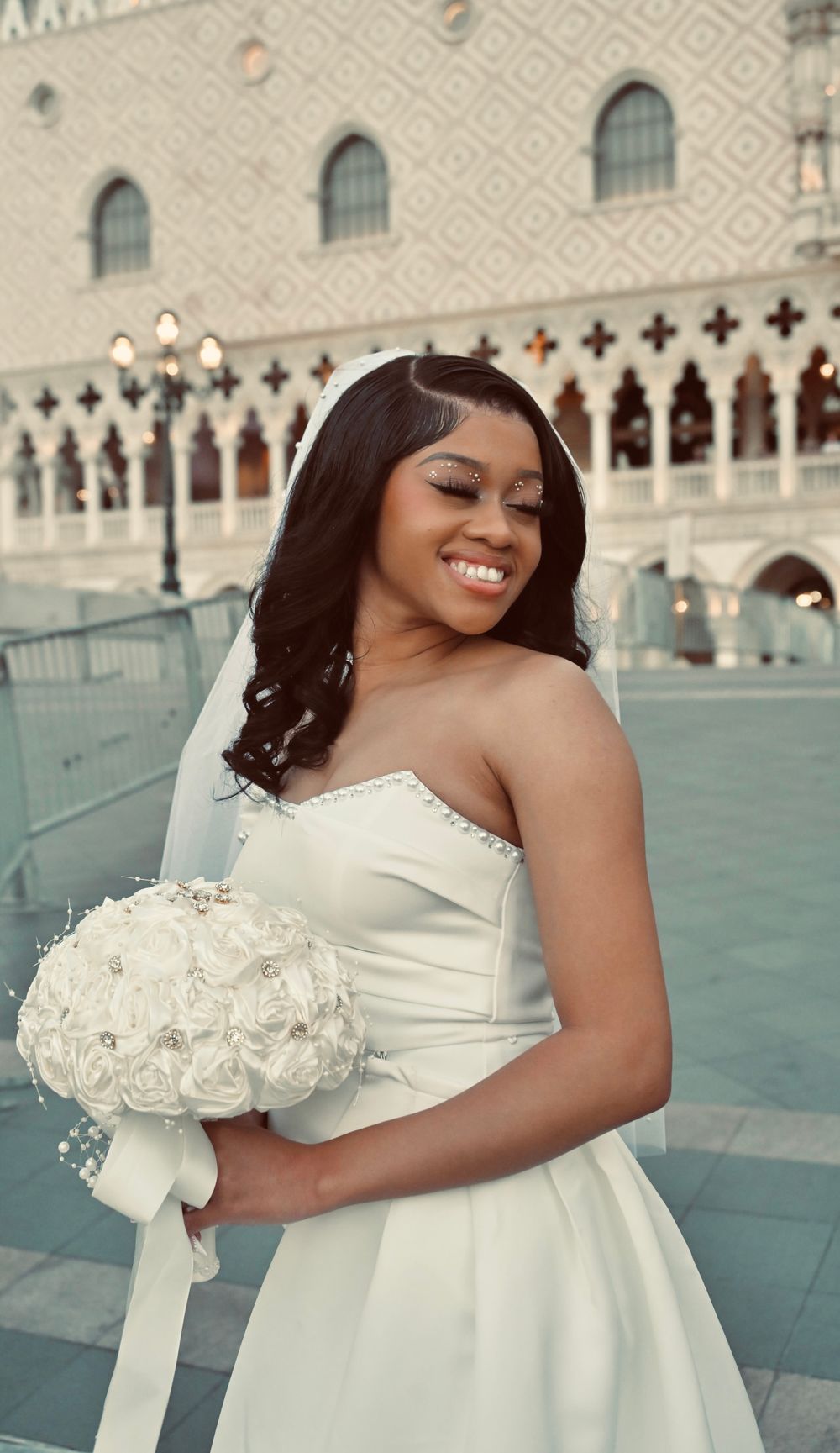 Beautiful bride in white strapless wedding dress holds bouquet outside The Venetian Las Vegas.