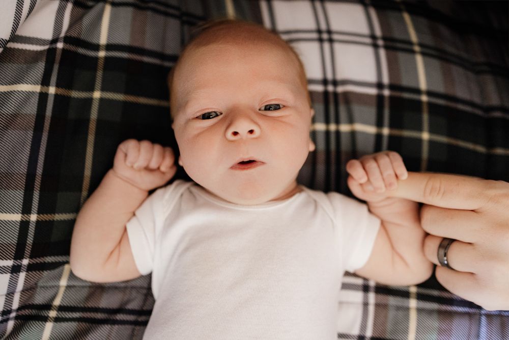 Newborn baby holds dad's finger during in-home photography session in Bay Area