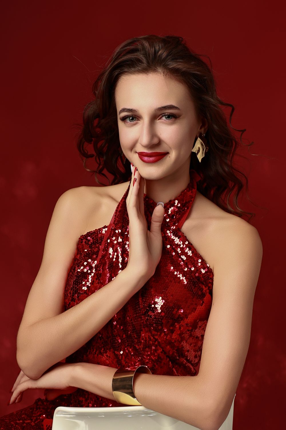 A glamorous photo series against a deep red background featuring a sequined red dress and elegant styling.