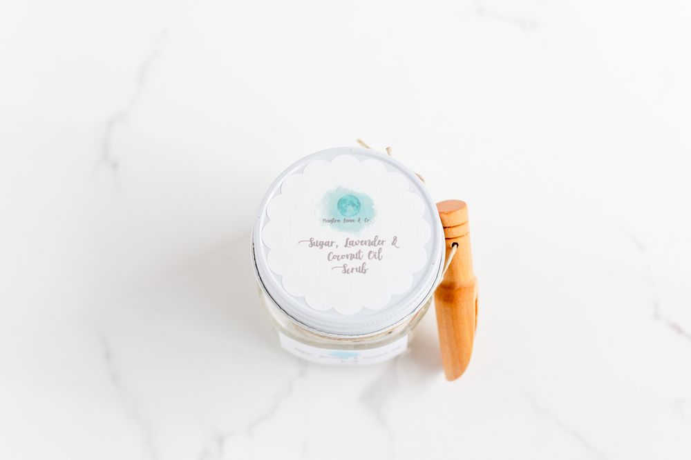 Glass container with orange wooden spoon shown on white marble surface.