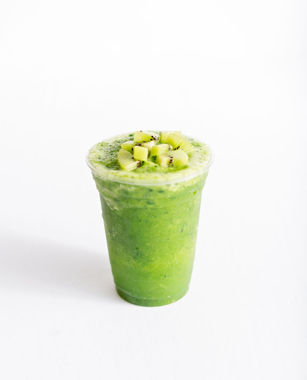 Fresh green avocado smoothie topped with diced fruit in a clear plastic cup.
Brand, product photography.