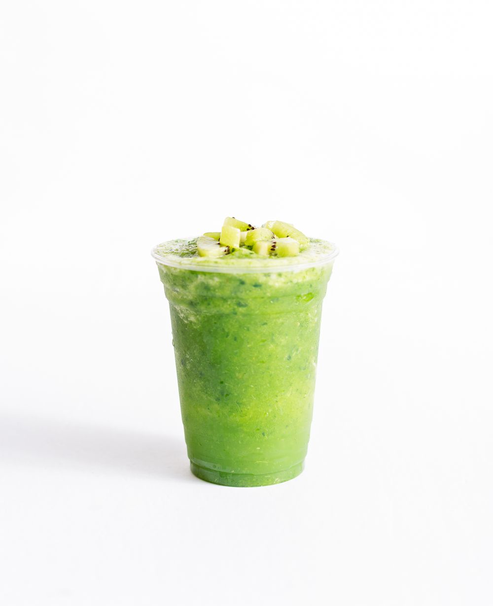 Vibrant green smoothie with avocado chunks on top in a clear container.
Brand, product photography.