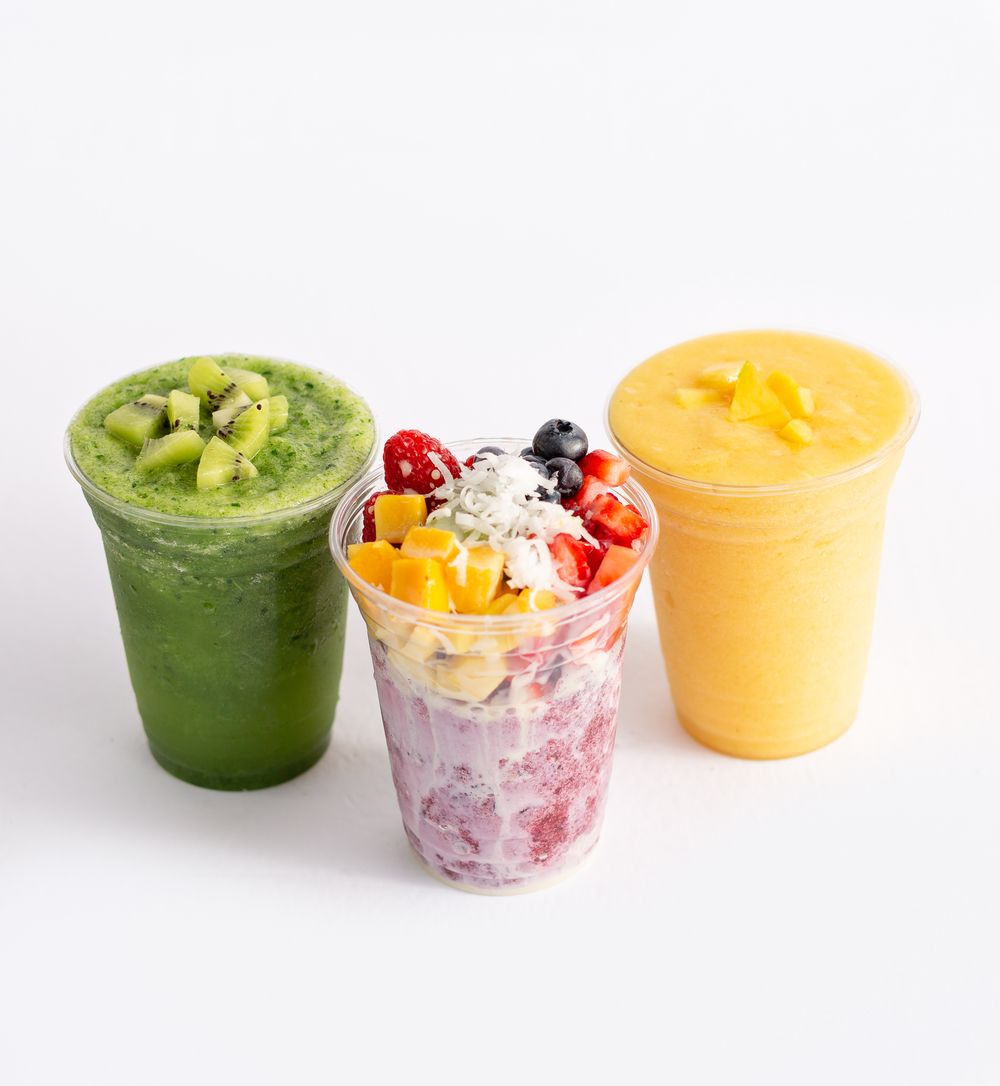 Colorful fruit smoothies in cups with fresh fruit garnishes on white background.
Brand, product photography.