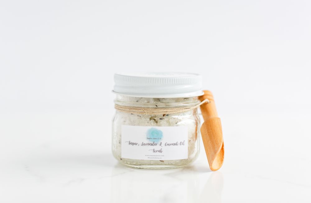 Bath salt jar with wooden scoop photographed from above on marble background.